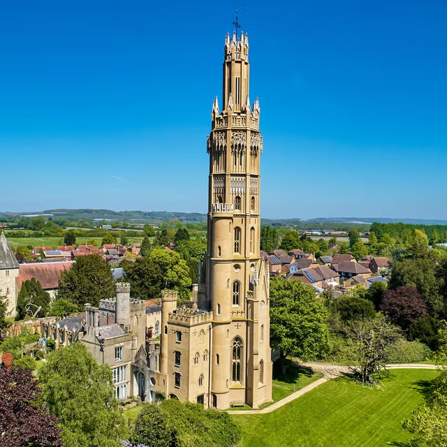 A Gothic-revival tower and campus building set in green grounds